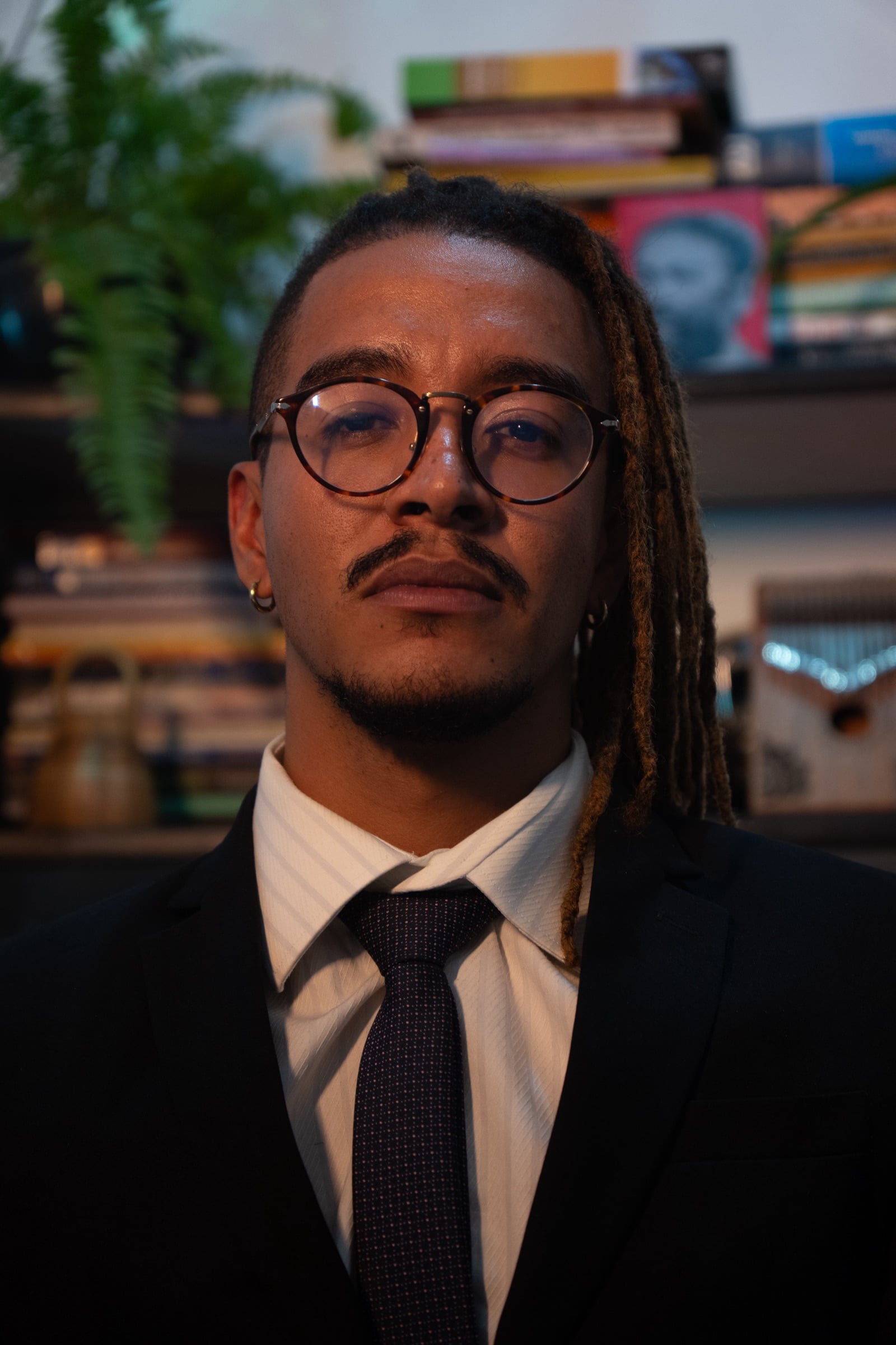 Retrato do advogado Thiago Farias, de terno escuro, diante de uma estante de livros